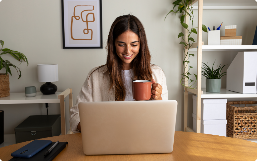 Woman working on laptop while drinking coffee at home